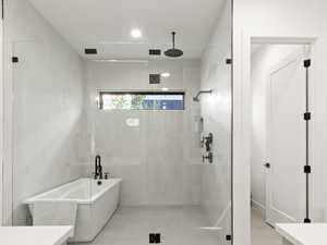 Full bath featuring vanity, a shower stall, a freestanding tub, and tile walls