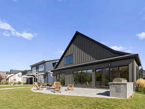 Rear view of house featuring board and batten siding, a yard, a patio area, and a fire pit