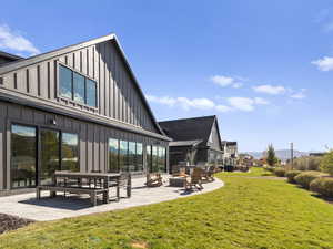 Back of house featuring board and batten siding, a patio area, a lawn, and a mountain view