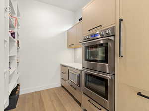 Kitchen with stainless steel appliances, light wood finished floors, light brown cabinets, light countertops, and modern cabinets