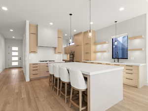 Kitchen with modern cabinets, pendant lighting, light brown cabinets, and recessed lighting