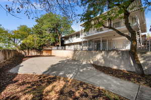 Back of house featuring a balcony and a fenced backyard