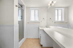 Bathroom featuring wainscoting, vanity, a shower stall, and light tile patterned floors
