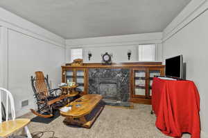 Carpeted living area with a premium built in fireplace and a textured ceiling