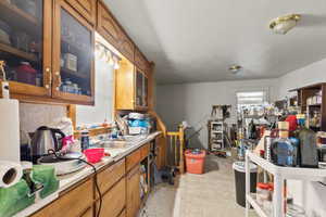 Kitchen featuring brown cabinets, glass insert cabinets, light countertops, light tile patterned floors, and a textured ceiling