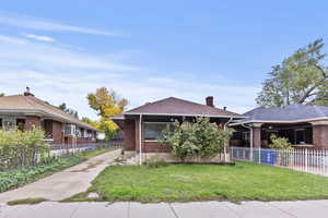 Bungalow-style home featuring a chimney, brick siding, and roof with shingles