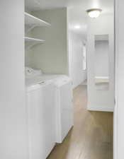 Laundry room with washer and clothes dryer and light wood-style flooring