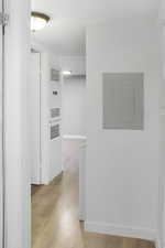 Corridor with electric panel and light wood-type flooring