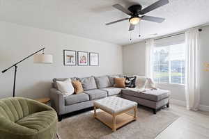 Living room with a textured ceiling, wood finished floors, and a ceiling fan