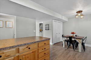 Kitchen featuring a textured ceiling, light wood finished floors, dark countertops, and decorative light fixtures