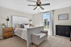 Bedroom featuring light colored carpet, a textured ceiling, and a ceiling fan