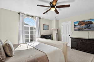 Bedroom with light carpet, a textured ceiling, and a ceiling fan