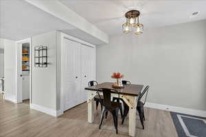 Dining space with a textured ceiling, light wood-style flooring, and a chandelier
