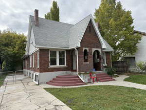 English style home with brick siding, a chimney, a gate, and roof with shingles