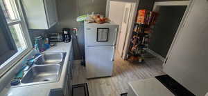 Kitchen featuring freestanding refrigerator, light wood-style flooring, light countertops, and white cabinets