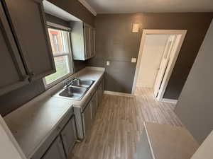 Kitchen featuring light countertops, light wood-type flooring, and gray cabinets