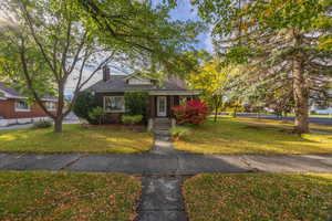 Bungalow featuring a front lawn, a chimney.
