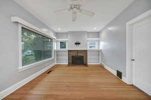 Lliving room featuring light wood-floors, a brick fireplace, ceiling fan.