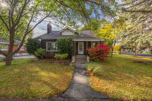Bungalow featuring a front yard, a chimney, covered porch.