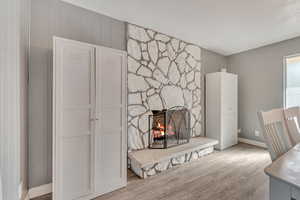 Detailed view of a stone fireplace, wooden walls, and wood finished floors
