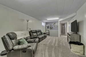 Living room featuring light carpet, wood walls, and a wainscoted wall