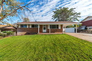 Ranch-style home featuring concrete driveway, covered porch, brick siding, and a carport