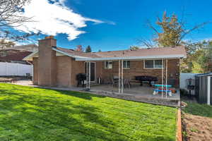 Back of house with a patio area, brick siding, a chimney, and a shingled roof
