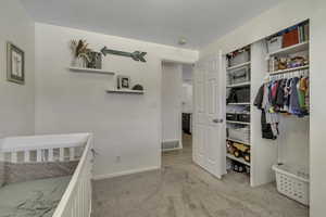 Bedroom with light colored carpet and a closet
