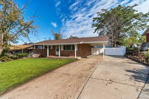 Ranch-style home featuring driveway, an attached carport, brick siding, roof with shingles, and a porch