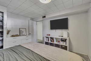 Carpeted bedroom featuring baseboards and a drop ceiling