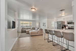 Kitchen featuring a breakfast bar area, light wood-style flooring, stainless steel appliances, and light countertops