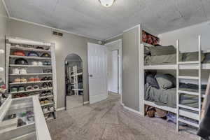 Bedroom with light carpet, ornamental molding, and arched walkways