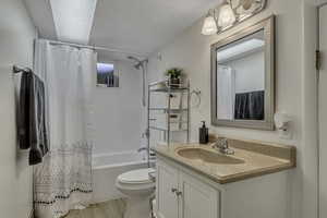 Full bathroom with light wood finished floors, shower / bathtub combination with curtain, and vanity