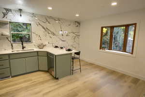 Kitchen with a peninsula, recessed lighting, a breakfast bar area, dishwasher, and light stone counters