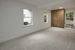 Unfurnished bedroom featuring light carpet and beamed ceiling