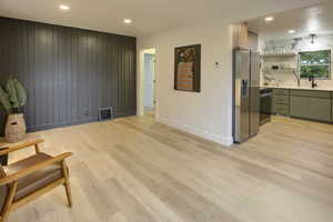 Living area with recessed lighting, light wood-style floors, and wood walls