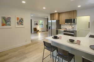 Kitchen with appliances with stainless steel finishes, light wood finished floors, recessed lighting, light countertops, and tasteful backsplash