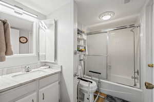 Bathroom featuring a textured ceiling, vanity, bath / shower combo with glass door, and wood finished floors