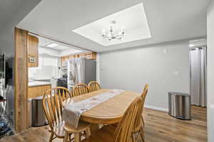 Dining space with a chandelier, a raised ceiling, and light wood finished floors