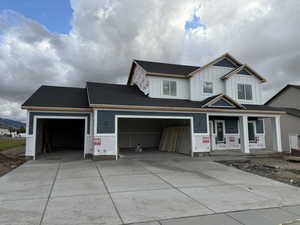 View of front of property featuring board and batten siding, covered porch, concrete driveway, and a shingled roof
