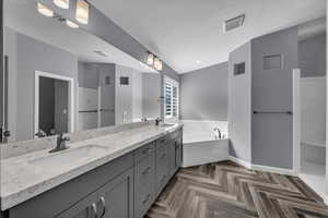 Bathroom featuring double vanity, a bath, and a textured ceiling