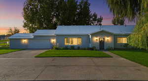Ranch-style home featuring concrete driveway, a lawn, a metal roof, and a garage