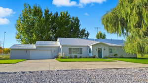 Ranch-style house with driveway, a metal roof, a front lawn, and an attached garage