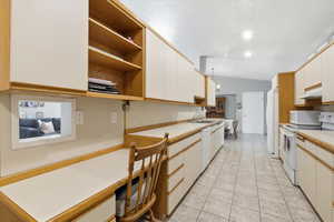 Kitchen with white appliances, open shelves, light countertops, white cabinets, and light tile patterned floors