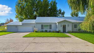 Single story home with concrete driveway, a metal roof, and a front yard