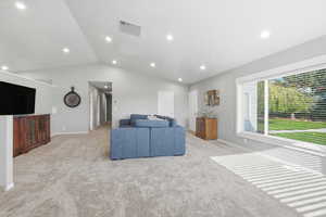 Living room with lofted ceiling, light colored carpet, and recessed lighting