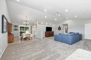 Living area with light carpet, a chandelier, high vaulted ceiling, light tile patterned floors, and recessed lighting