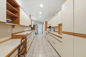 Kitchen with white appliances, open shelves, white cabinetry, light countertops, and vaulted ceiling