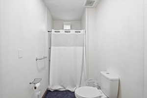 Full bathroom featuring a shower with shower curtain and toilet