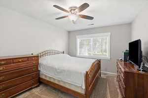 Carpeted bedroom with a ceiling fan and baseboards
